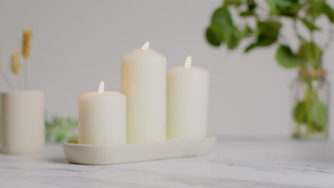 person wearing robe picking up towel at relaxing spa day with lit candles dried grasses and incense stick