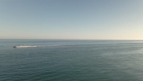 Fast-aerial-view-speeding-jet-ski-across-seascape-ocean-horizon-right-to-left