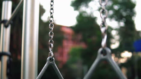 close up of steel triangular gymnastic rings hanging in an outdoor gym, selective focus