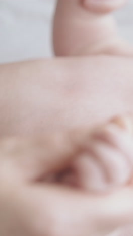 restless infant boy with plump cheeks lies on baby changing table and nurse practices hypertonus massage close view