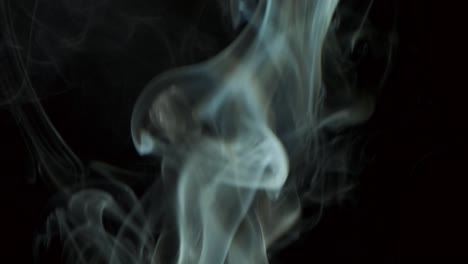 nubes de humo plateado que se elevan lentamente giros graciosos hacia arriba. humo de cigarro soplando de abajo hacia arriba. primer plano, aislado en fondo negro