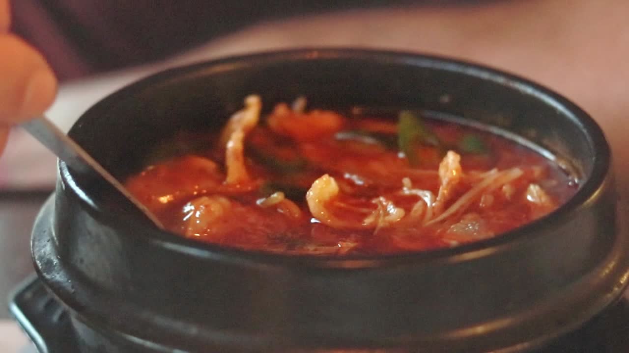 Eating a bowl of savory kimchi jjgae or kimchi stew, authentic traditional local South Korean food