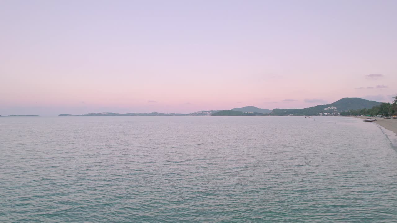 정박한 요트, 코코넛 야자수, 해변가 리조트를 포함하여 태국 코사무이의 보푸트 해변에서 해안 너머로 다채로운 4k 드론 일몰 바다 전망