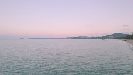 정박한 요트, 코코넛 야자수, 해변가 리조트를 포함하여 태국 코사무이의 보푸트 해변에서 해안 너머로 다채로운 4k 드론 일몰 바다 전망