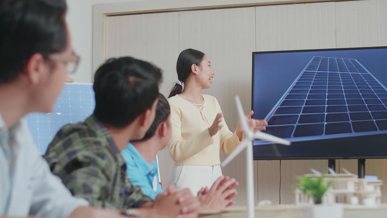 아시아 여성 엔지니어가 사무실에서 동료들에게 태양전지의 작업에 대해 발표하고 있습니다.