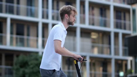 Young-businessman-walking-to-his-e-scooter-and-driving-off