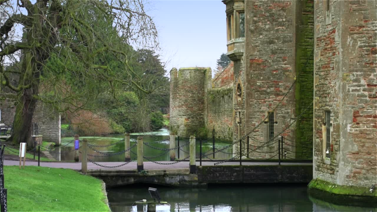 mirando a lo largo del foso, hacia el puente levadizo del castillo y las torres de la puerta principal del palacio medieval del obispo en wells, reino unido