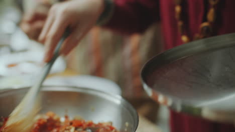 young woman learning indian cuisine under guidance of senior chef in kitchen