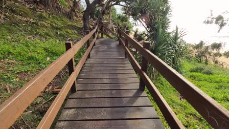 personal perspective of a surfer walking down boardwalk stairs and arriving at an australian beach at dawn