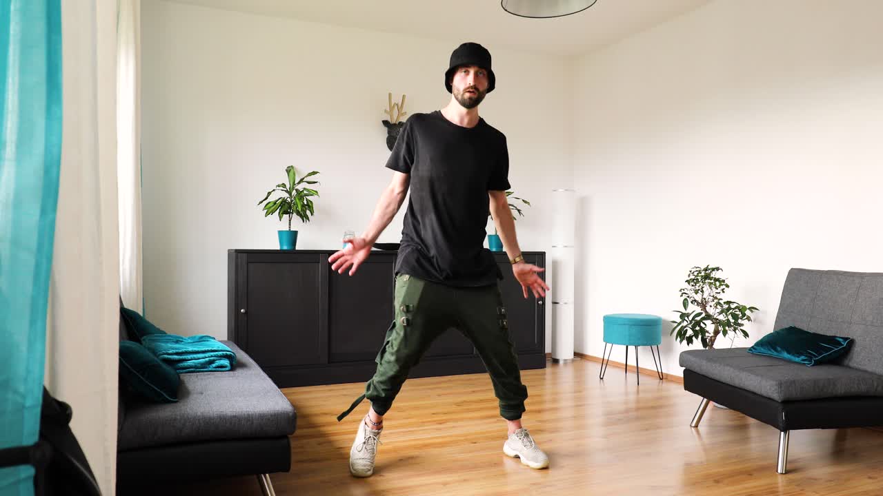 young man dances in the living room and trains his dance steps