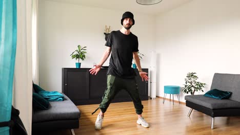young man dances in the living room and trains his dance steps