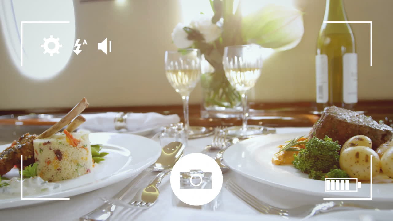 Camera interface animation over gourmet meal with wine glasses on elegant table