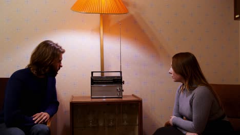 una pareja escuchando una radio antigua.