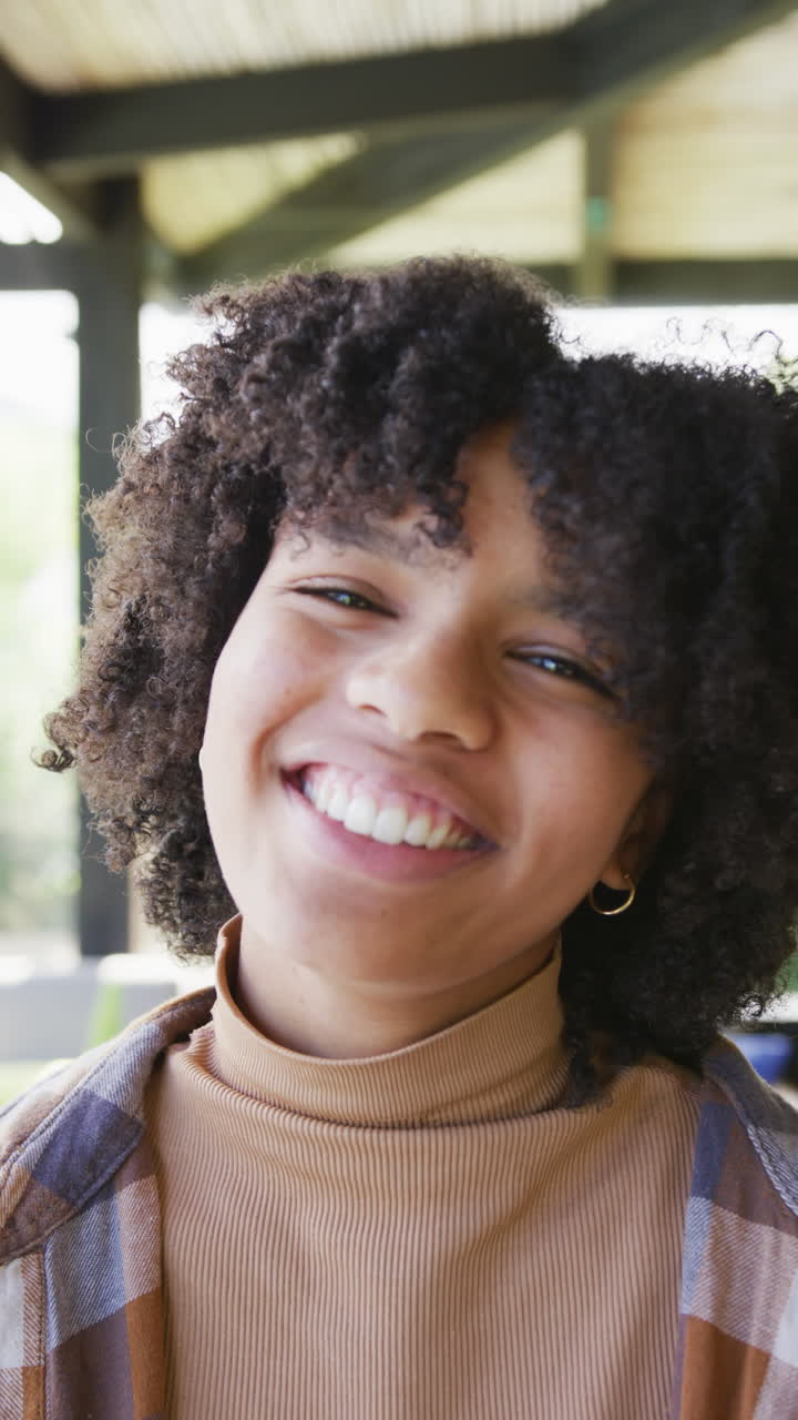 Vertical video of portrait of happy african american teenager girl at home, slow motion