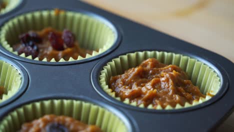 adding raisins to batter inside of pan for vegan pumpkin muffins using real roasted pumpkin in bowl healthy dairy-free recipe vegan