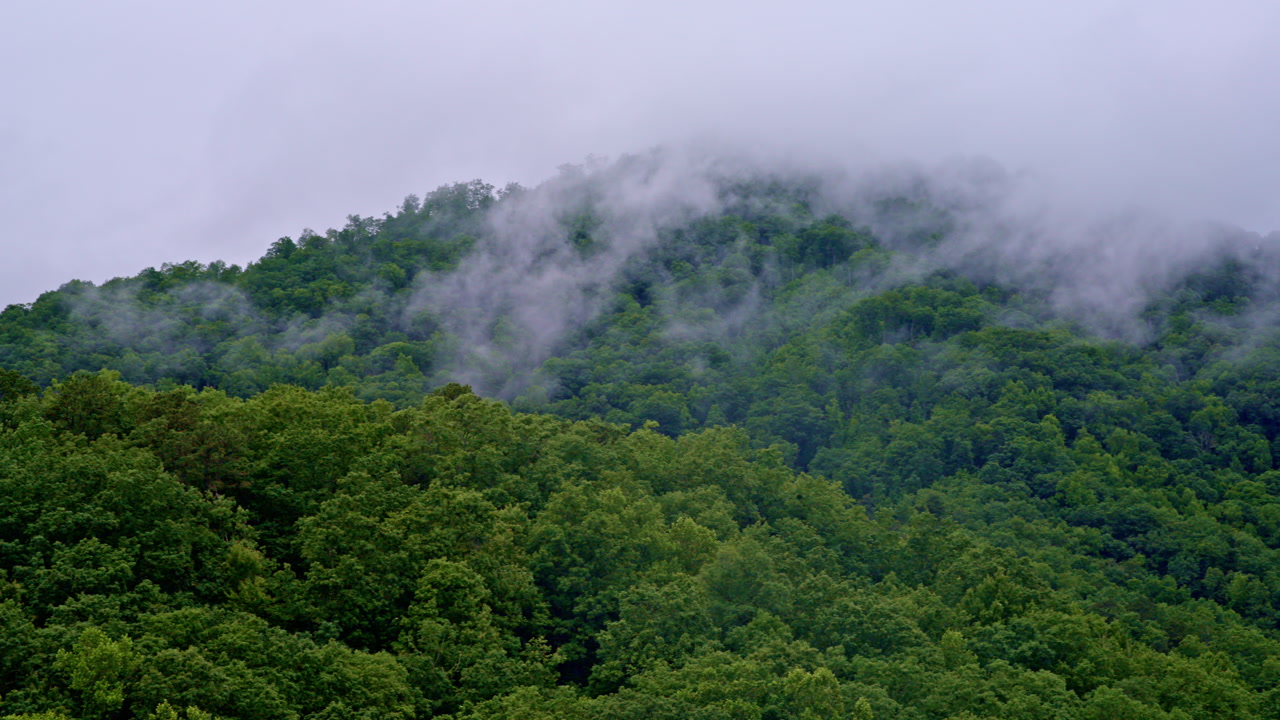 Drone sweeps dramatically over fog-bound mountain ranges.