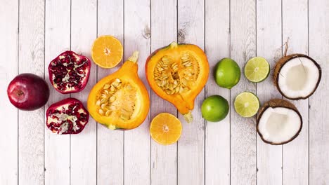 pomegranate, oranges, pumpkins, limes and coconuts appear on wooden theme. stop motion