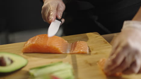 chef's gloved hands slicing fresh salmon on a cutting board