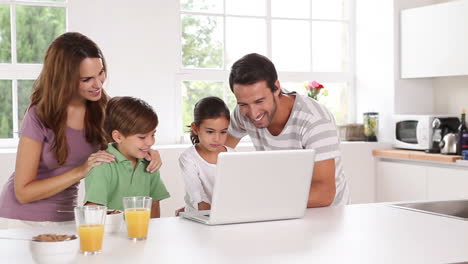 Familia-Usando-Una-Computadora-Portátil-Blanca-En-La-Cocina