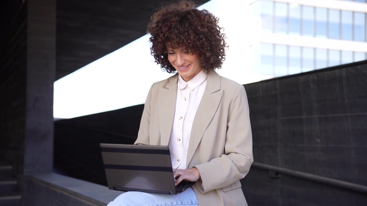 Una donna professionista che utilizza un laptop in un ambiente urbano contemporaneo si gode il suo lavoro.