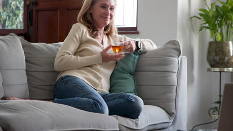 relaxing at home, senior woman enjoying tea on cozy sofa