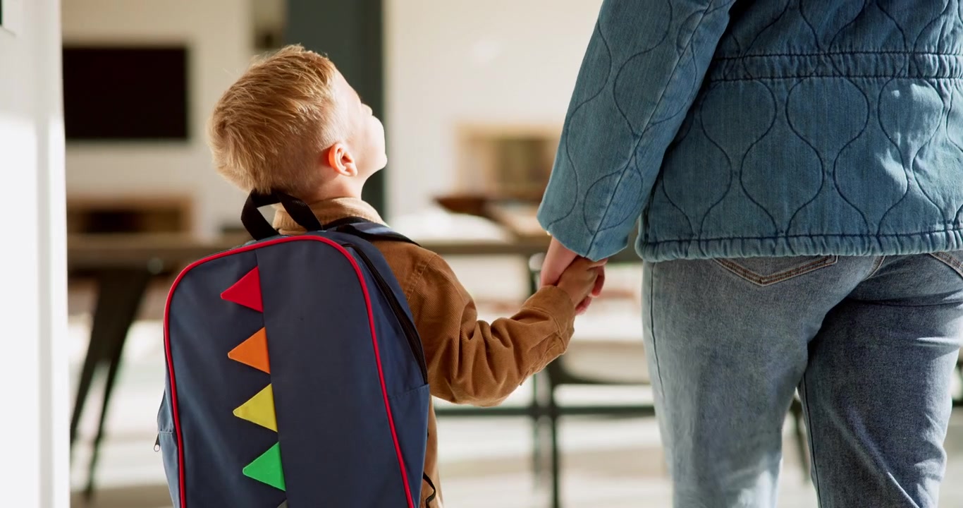 Mother Holding Hand of Young Son with Backpack Walking Indoors