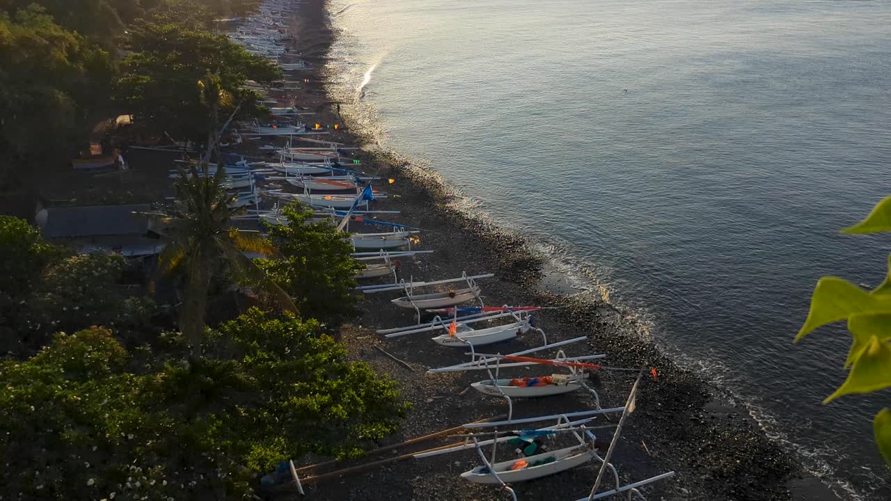 Mt Agung volcano with fishing boats moored on beach and ocean views with golden sunlight on tropical island of Bali in Amed, Indonesia
