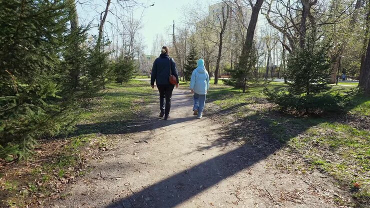 Deux personnes marchant sur un chemin de terre dans un parc ensoleillé