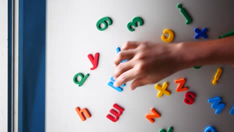 niño jugando con letras y números magnéticos en una pizarra