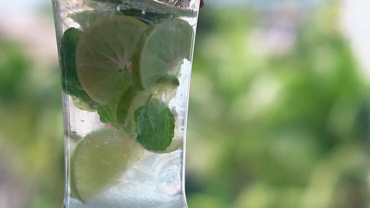 una lunga paglia arancione mescola un mojito fresco e freddo in un bicchiere alto