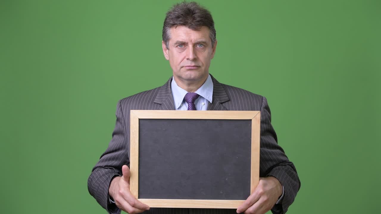 Mature handsome businessman against green background