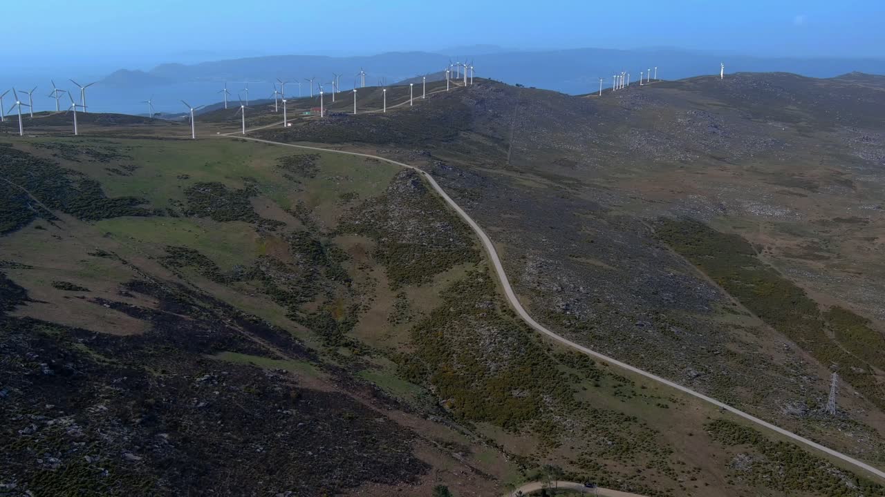 antena sobre la carretera de acceso que conduce a las turbinas eólicas giratorias en la ladera de galicia en españa