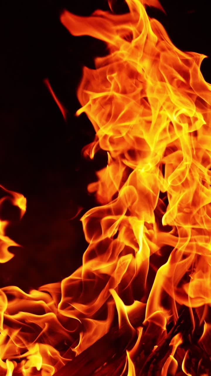 Big bonfire burning and producing a cloud of sparks flying up. Campfire close up at night. Vertical video