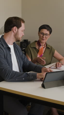 two people collaborating and discussing work at a table