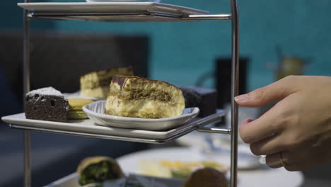 Slow-motion-shot-of-fresh-cakes-on-a-stand-with-one-being-taken-to-eat