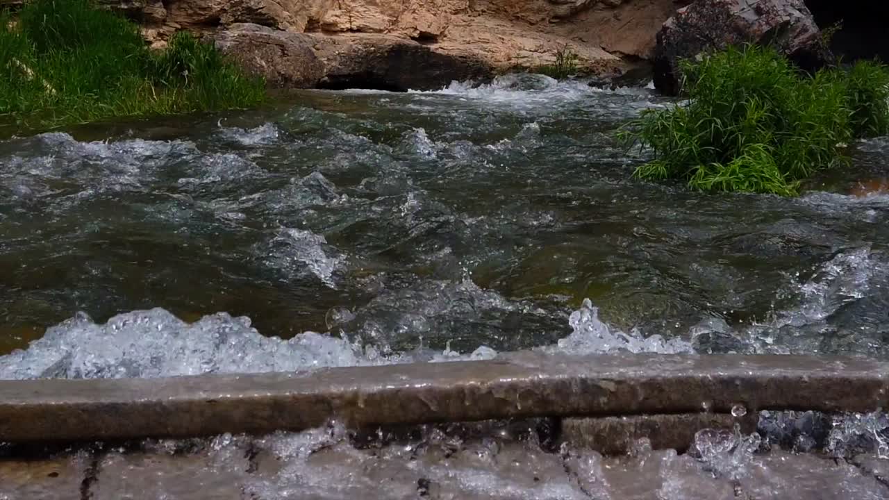 Água corrente de rio fluindo rapidamente sobre uma ponte