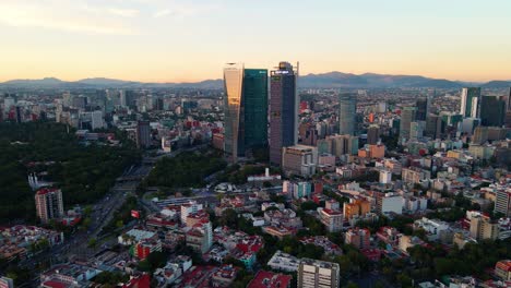 aerial view over the chapultepec cityscape, towards two high rise buildings, in mexico city, central america - rising, tilt down, drone shot