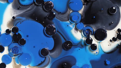 abstract art background of swirling white, blue and black colors, ink bubbles burst and react