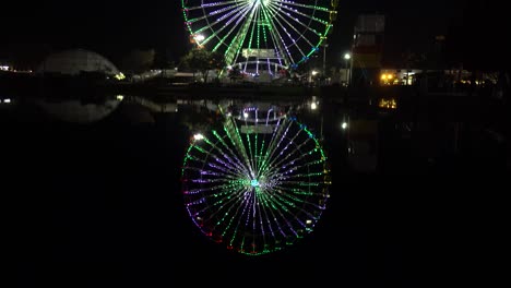 Suba-Desde-La-Reflexión-Sobre-El-Agua-Hasta-La-Rueda-De-La-Fortuna-Con-Luces-En-La-Feria-Estatal-De-Florida-Por-La-Noche