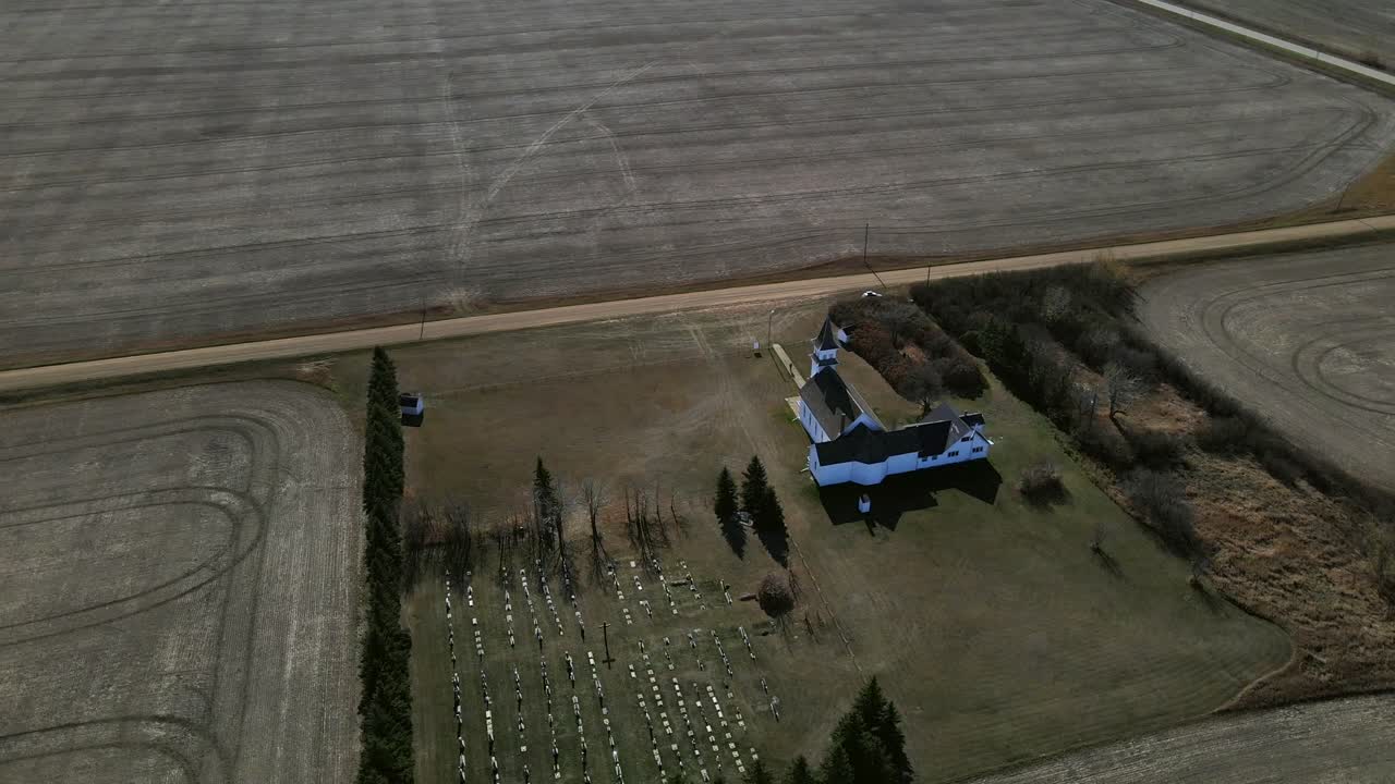 Orbiting drone high above St. Boniface church in Flagstaff County, Alberta. Quick cinematic camera movement revealing beautiful old building underneath. Aerial footage in 4k on sunny prairie day