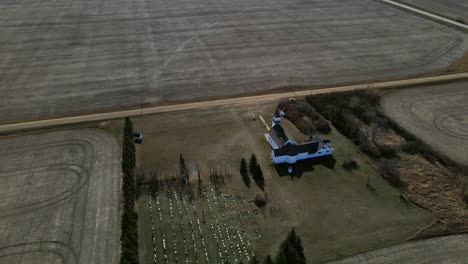 orbiting drone high above st. boniface church in flagstaff county, alberta. quick cinematic camera movement revealing beautiful old building underneath. aerial footage in 4k on sunny prairie day