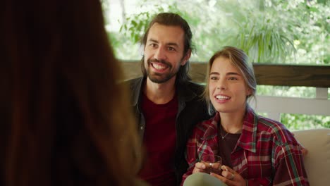 una pareja de un chico moreno y una chica rubia en una camisa a cuadros roja se comunican con otra chica en un gazebo en la naturaleza