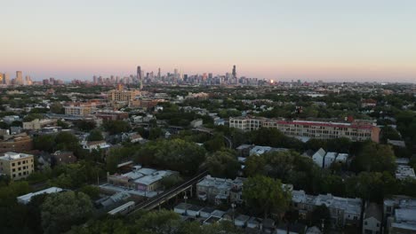 El-Dron-Desciende-Cuando-El-Tren-Del-Metro-Cta-Entra-En-El-Marco,-El-Fondo-Del-Horizonte-De-Chicago