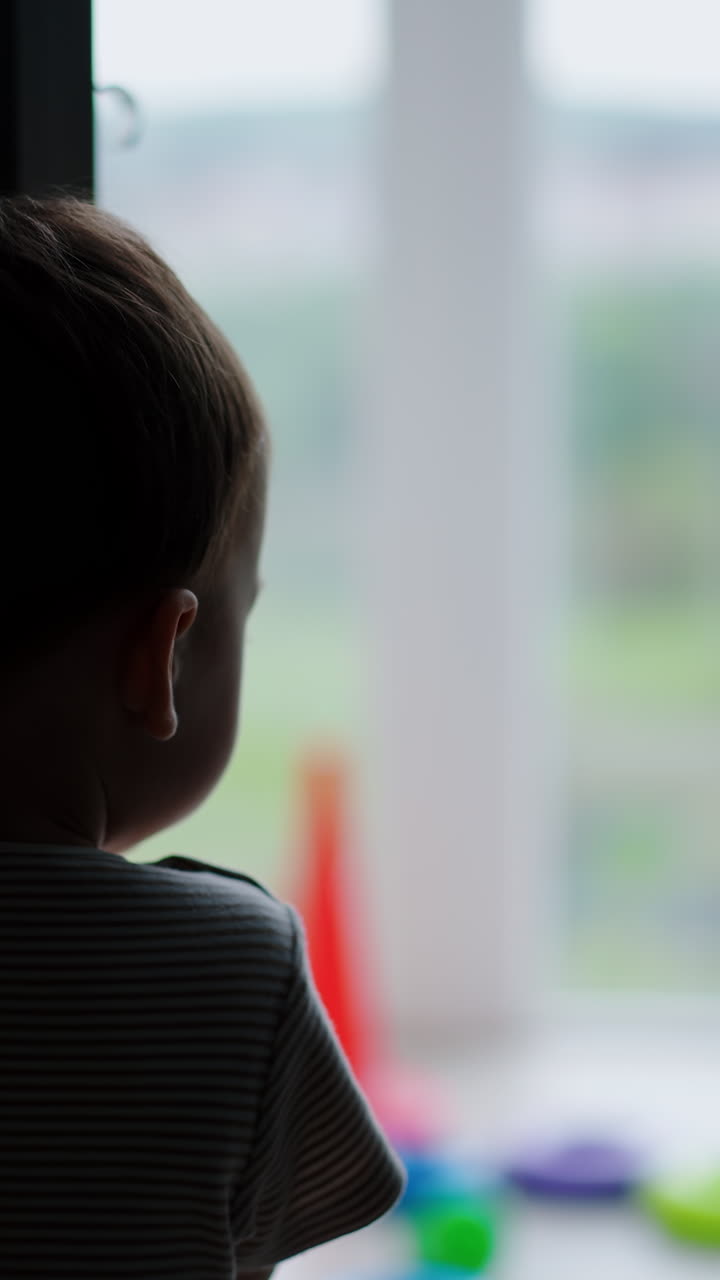 Agile little toddler opens the door. Kid walks to a balcony where his toys are. Vertical video