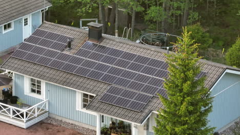 Drone-circling-the-solar-roof-of-a-eco-friendly-house,-on-a-sunny-summer-evening