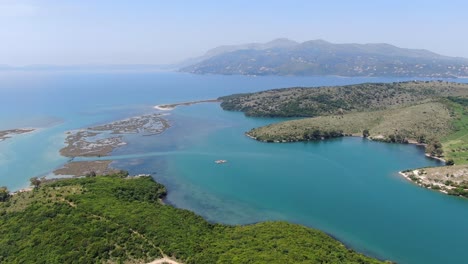 vista de avión no tripulado en albania volando sobre un amplio río y un paisaje verde junto al mar con montañas en la parte posterior