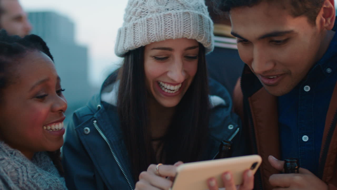 young woman using smartphone showing group of diverse friends social media entertainment enjoying rooftop party at sunset