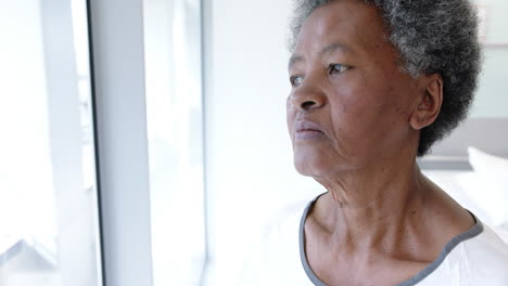 African-american-female-senior-patient-looking-out-window-in-hospital-room,-slow-motion