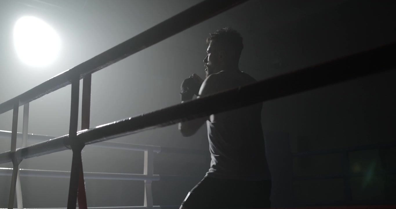 Male Boxer Shadow Boxing in a Dark, Smoky Ring with Spotlight