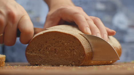 cut bread with a knife on a wooden board closeup in the kitchen. shred